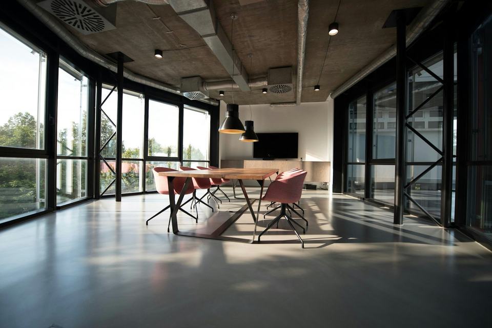 An empty modern meeting room with a wood table, chairs, and large windows.